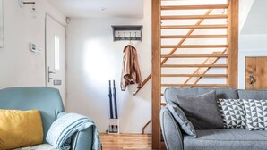 Una sala de estar con sofá, sillón, escalera de madera y perchero.
