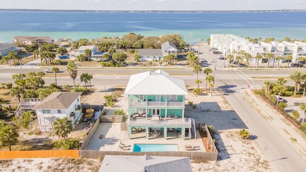 A beachfront property with a pool, a two-story building, and a view of the ocean.