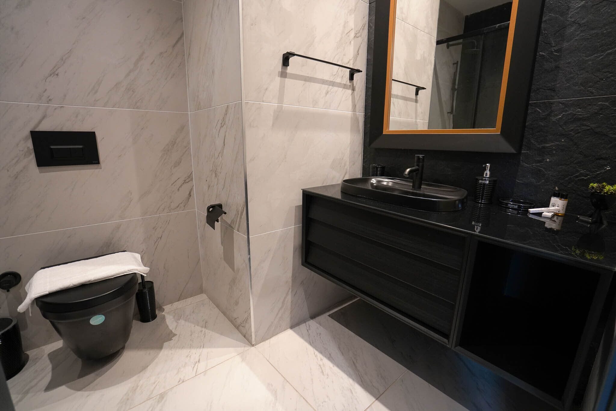 A modern bathroom with a black sink, a large mirror, and a marble floor.