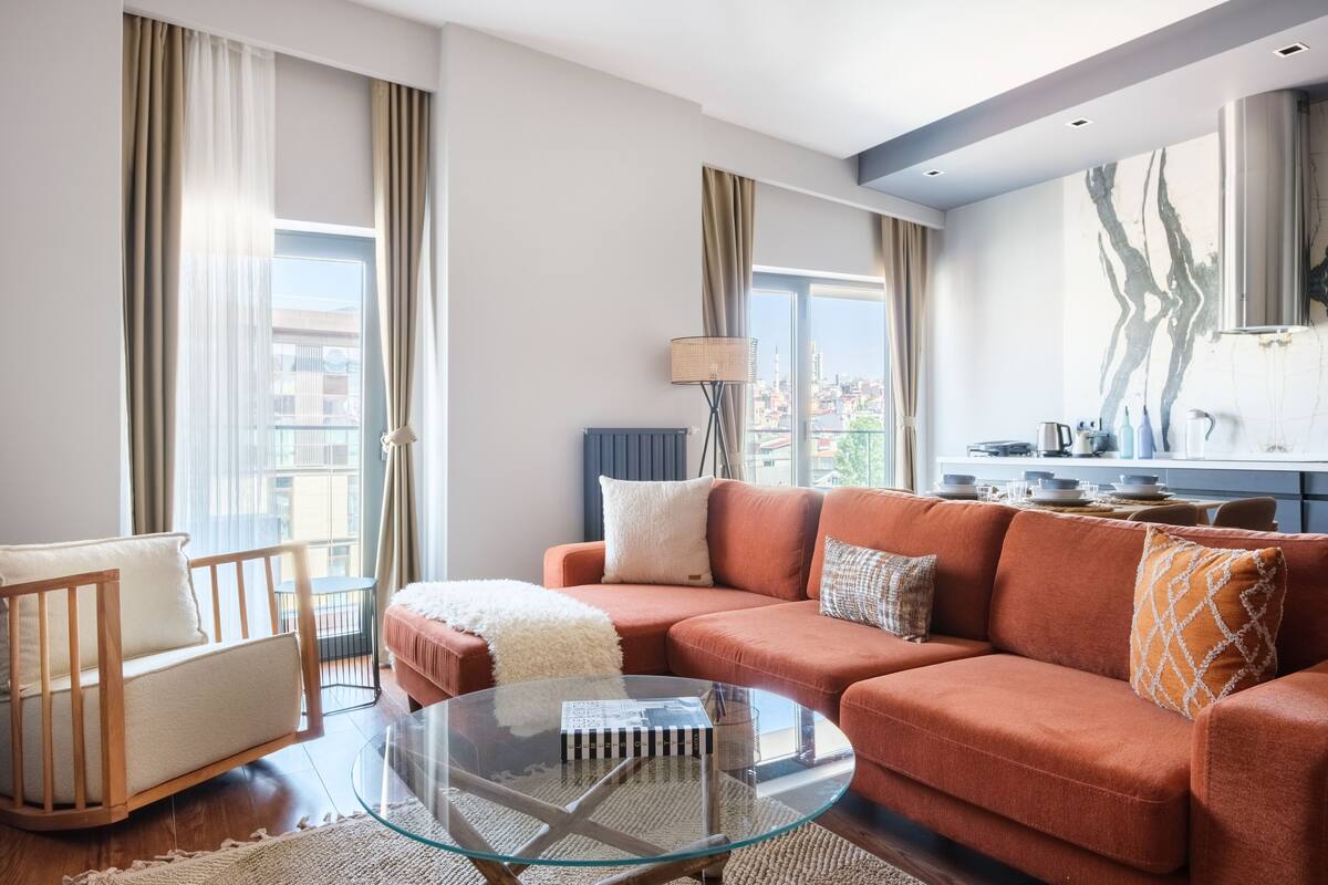 A modern living room with a glass coffee table, a red sofa, and a white armchair.