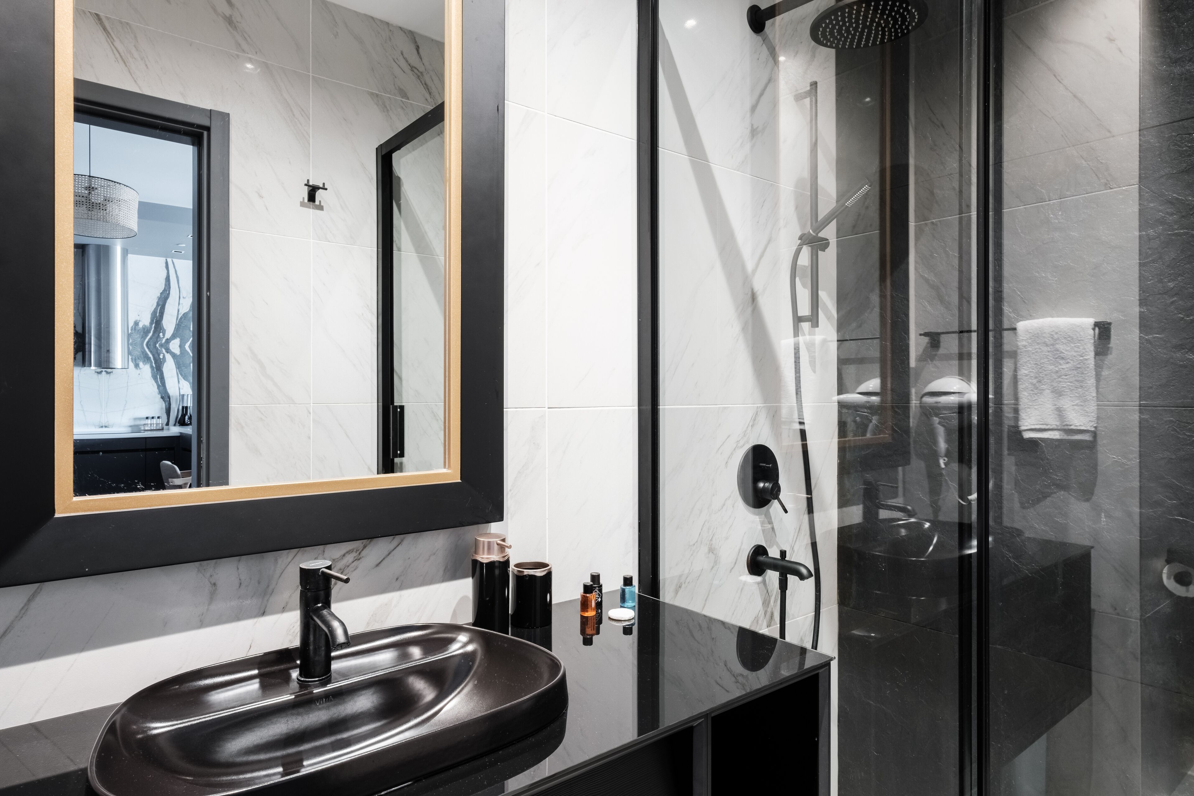 A modern bathroom with a black sink, a large mirror, and a glass-enclosed shower area.