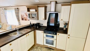 Una cocina compacta con microondas, estufa, horno y fregadero.