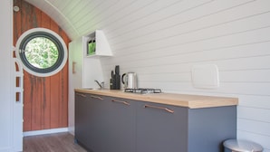 Una cocina moderna con encimera de madera, armarios grises y un ventanal redondo.