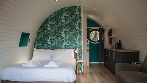 Un dormitorio pequeño con cama, una mesita, un sofá y vistas al exterior a través de una ventana.