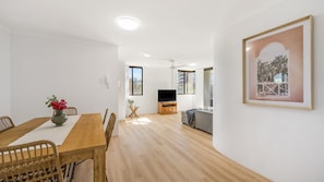 A modern living space with a dining area, a flat-screen TV, and a framed picture on the wall.