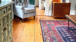 A room with a grey armchair, a wooden dresser, a patterned rug, and a green door. - Historic Kennebunkport home only 0.3 miles to Dock Square (Kennebunkport)