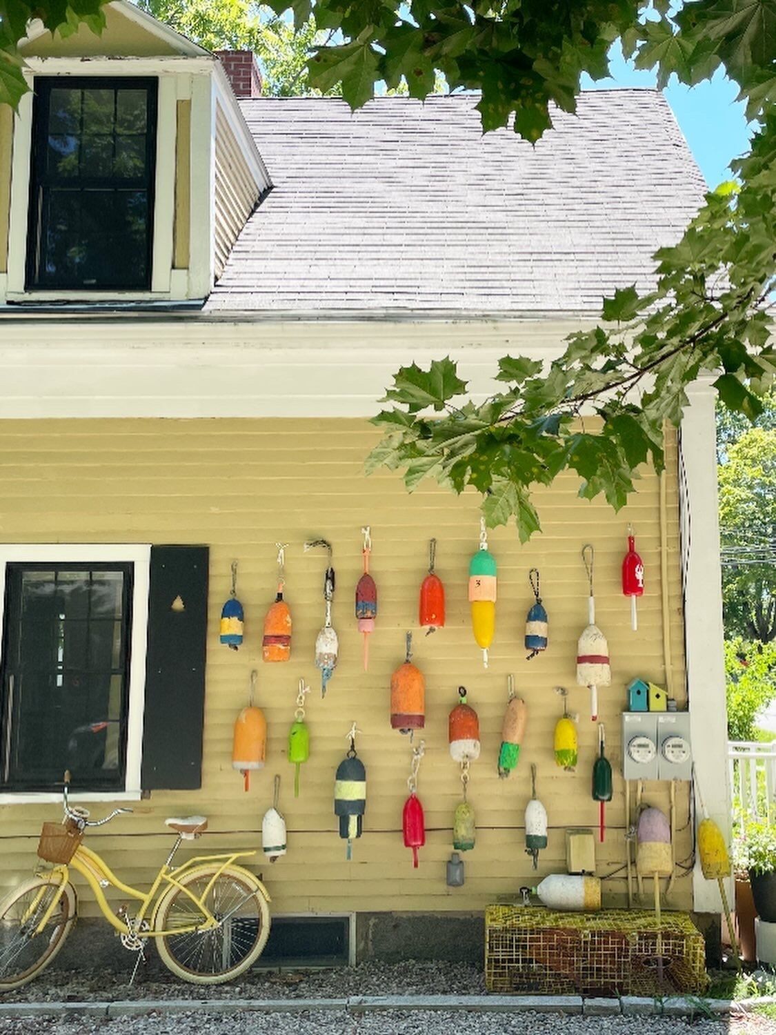 A yellow bicycle parked in front of a building with a row of colorful buoys hanging on the wall.