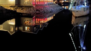 A waterfront property with a house featuring illuminated signage and a dock with a sailboat. - Historic Kennebunkport home only 0.3 miles to Dock Square (Kennebunkport)