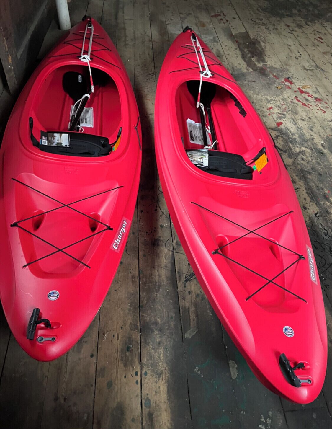 Deux kayaks rouges équipés de barres transversales et portant une étiquette sur laquelle on peut lire « Charger ».