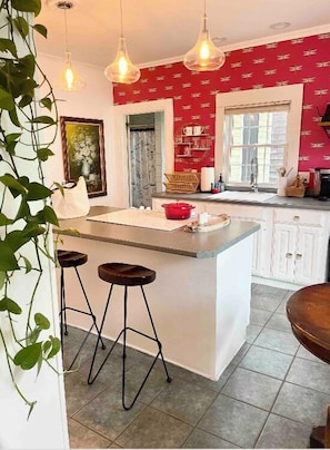 A kitchen with a central island, bar stools, pendant lights, and a red patterned wall. - Historic Kennebunkport home only 0.3 miles to Dock Square (Kennebunkport)