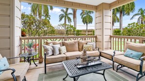 A covered outdoor seating area with a beige sofa, two armchairs, a small table, and a potted plant. - Pili Mai at Poipu #15J By Parrish Kauai - great central Poipu location, walkabl (Koloa)