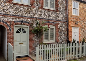 A charming two-story residence with a white picket fence and a small garden area.