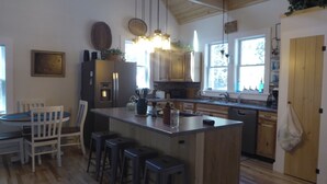 Una cucina con mobili in legno, un'isola centrale con sgabelli, un frigorifero e un lavello.