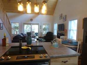 A kitchen with a stove, a dining table with chairs, a TV, and a fireplace.