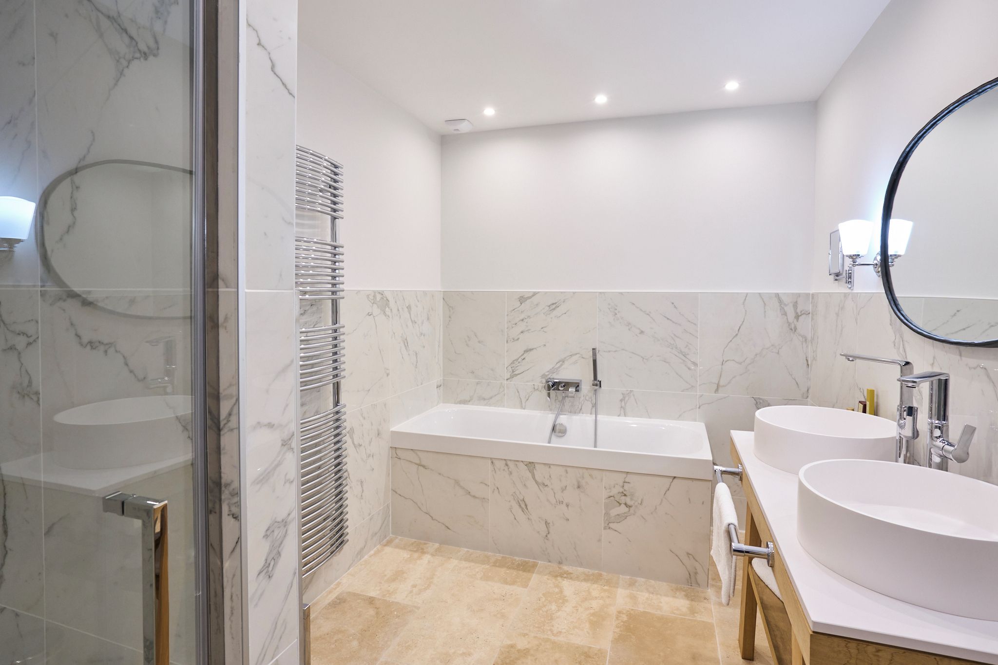A modern bathroom with a glass shower enclosure, a freestanding bathtub, and two sinks with vanity mirrors.