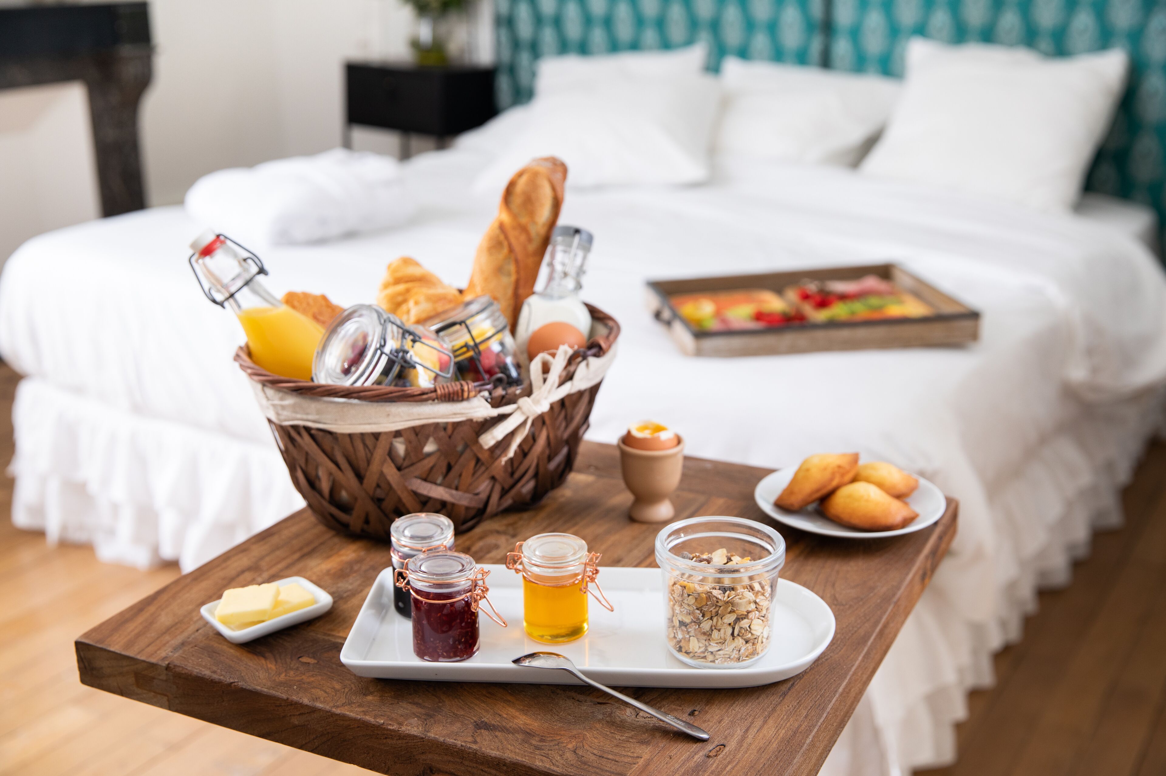 Ett frukostbricka med bröd, ägg och sylt står på ett träbord i ett hotellrum.