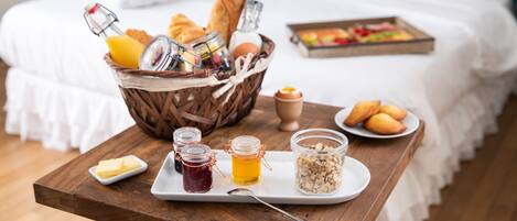 Ett frukostbricka med bröd, ägg och sylt står på ett träbord i ett hotellrum.