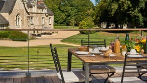 Mesa de comedor al aire libre con vista a un edificio histórico y un césped cuidado.