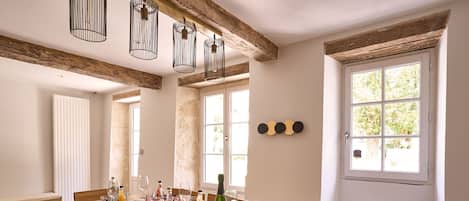 A dining area with a wooden table set for six, surrounded by chairs. There are hanging light fixtures above the table.