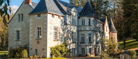 A large, historic stone building with multiple towers and a central courtyard.