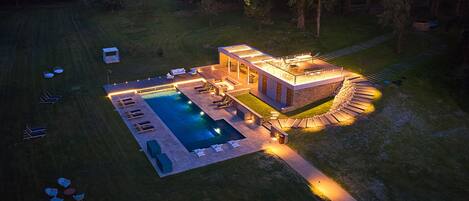 A modern house with a swimming pool, outdoor seating, and a stone pathway.