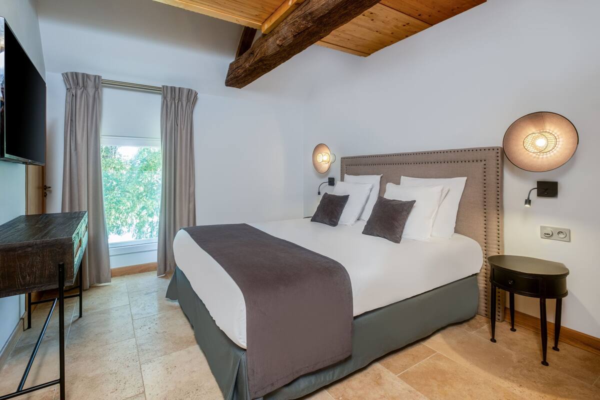 Ein Schlafzimmer mit Bett, Nachttischen, einem Schreibtisch und einem Fernseher.