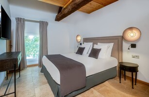 Un dormitorio con cama, mesitas de noche, escritorio y televisor.