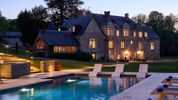 Una casa grande y histórica con piscina y sillones de descanso.