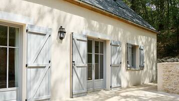 A building with four white doors and windows, a stone wall, and a tiled walkway.