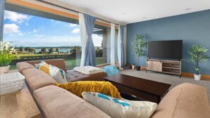 A modern living room with a large window, a flat-screen TV, and a comfortable seating area.
