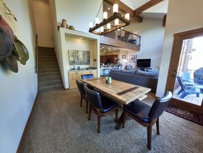 Amplia sala de estar con mesa de comedor, sillas, sofá y balcón con mobiliario exterior.
