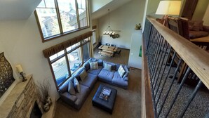 A spacious living area with a large sectional sofa, a dining table, and a staircase leading to an upper level. - Magnificent Townhome! Epic Mountain Views! Heated Pool! 2 Miles to Purgatory (durango)