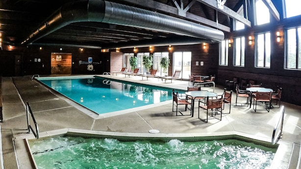 An indoor swimming pool with a hot tub, lounge chairs, and tables. - Magnificent Townhome! Epic Mountain Views! Heated Pool! 2 Miles to Purgatory (durango)