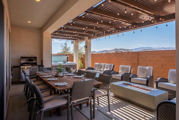 An outdoor patio with a dining table set for four, surrounded by wicker chairs. - Arcadia 47 | FAMILY FUN * Arcades * Games * PRIVATE HOT TUB (Santa Clara)