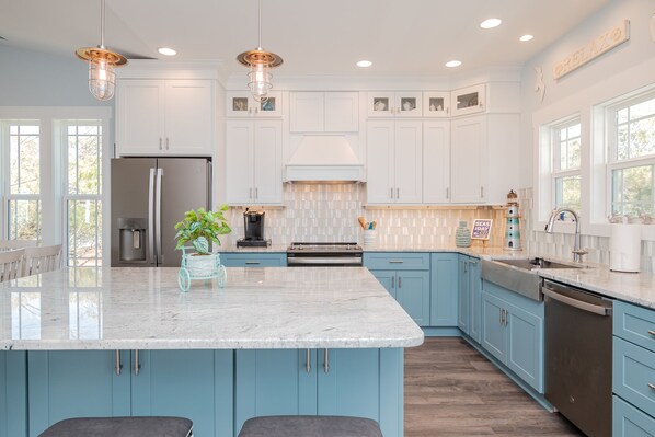 A modern kitchen with white cabinets, a large island, and pendant lighting.