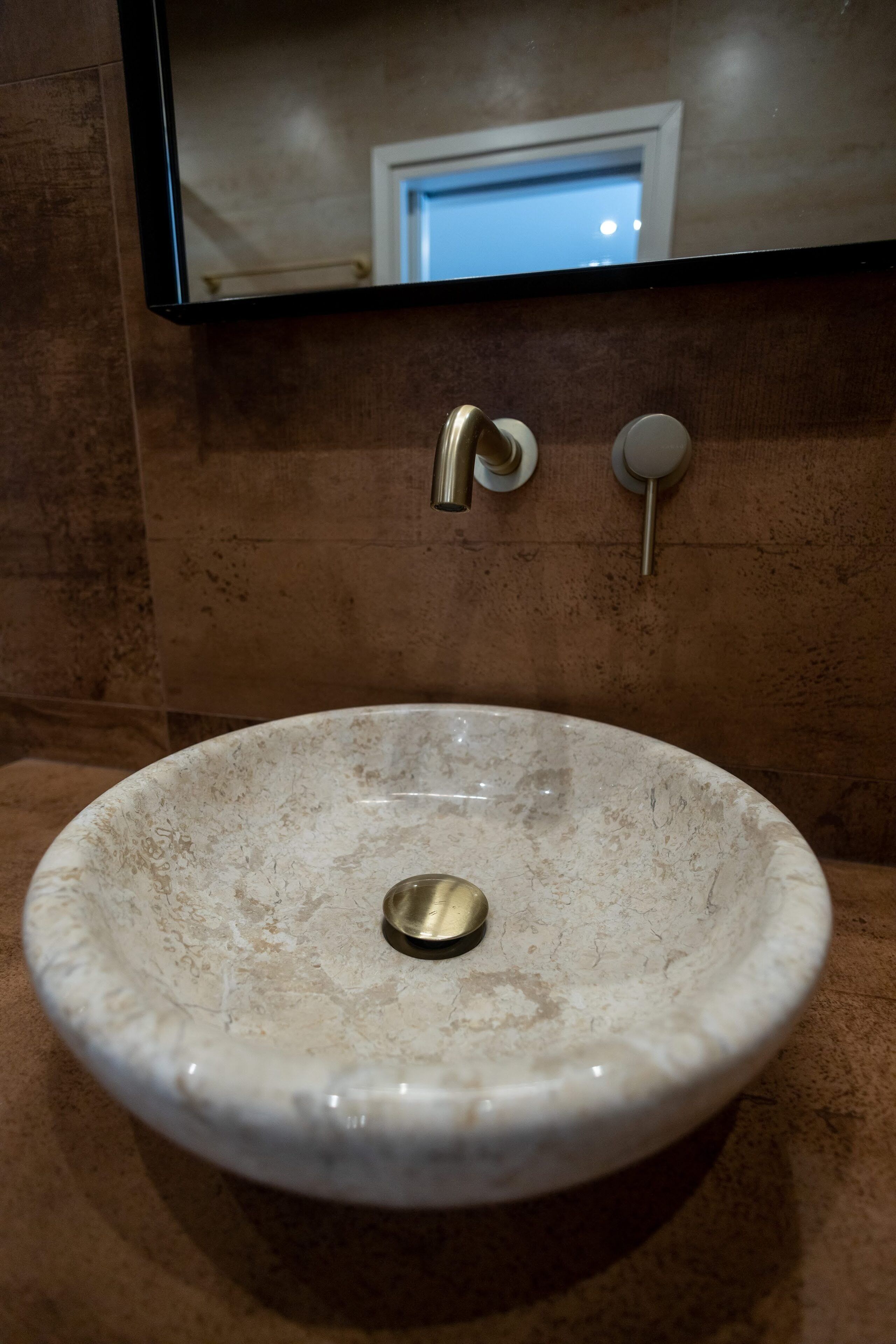 Un lavabo de salle de bain avec un receveur en marbre, un robinet et un miroir au-dessus.