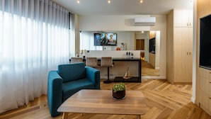 A modern living room with a blue sofa, a wooden coffee table, and a TV in the background. - Triple A - Kolokotroni 62 (Athens)