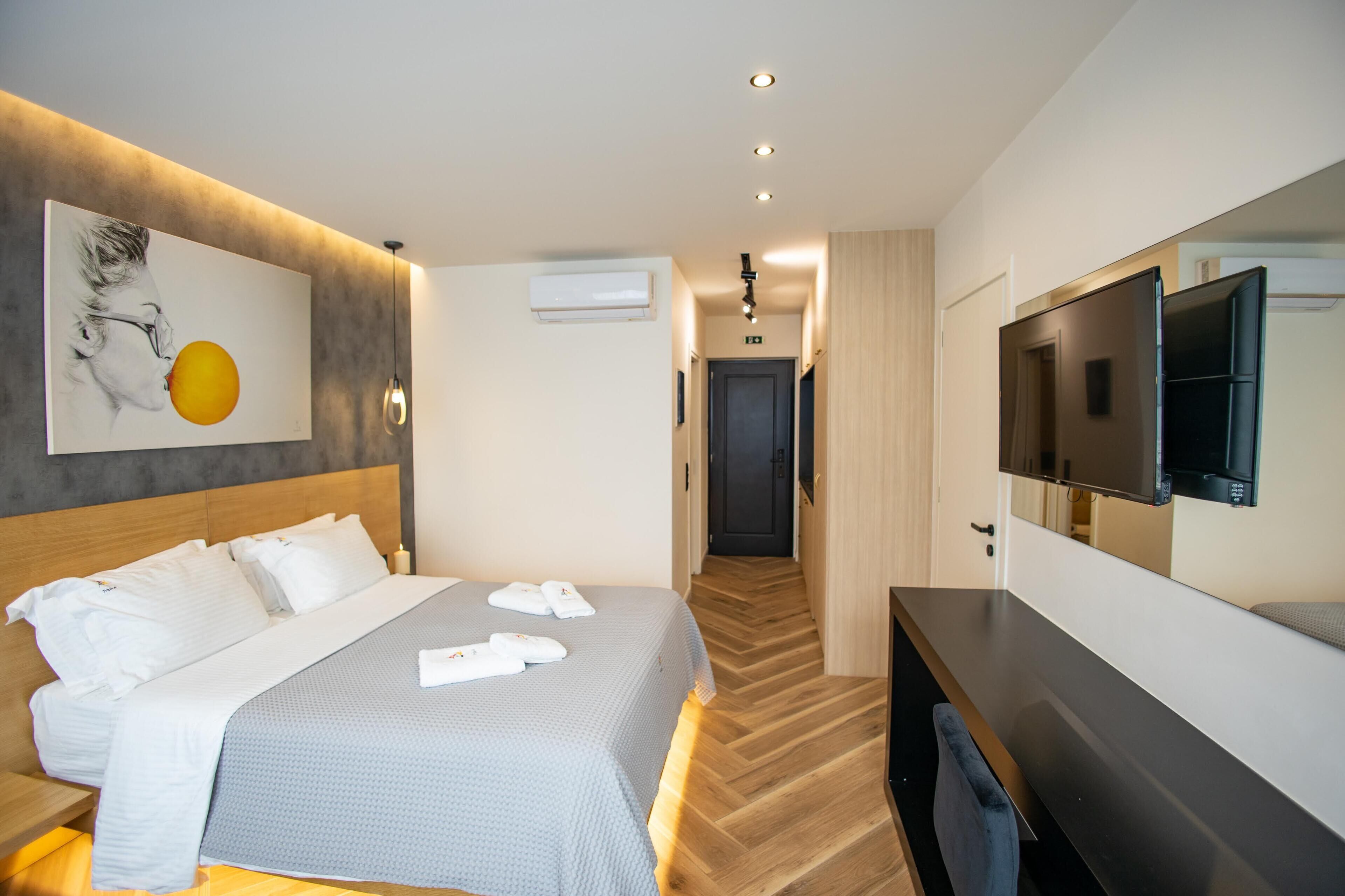 Une chambre d’hôtel moderne dotée d’un grand lit, d’une télévision à écran plat et d’un couloir menant à la salle de bain.