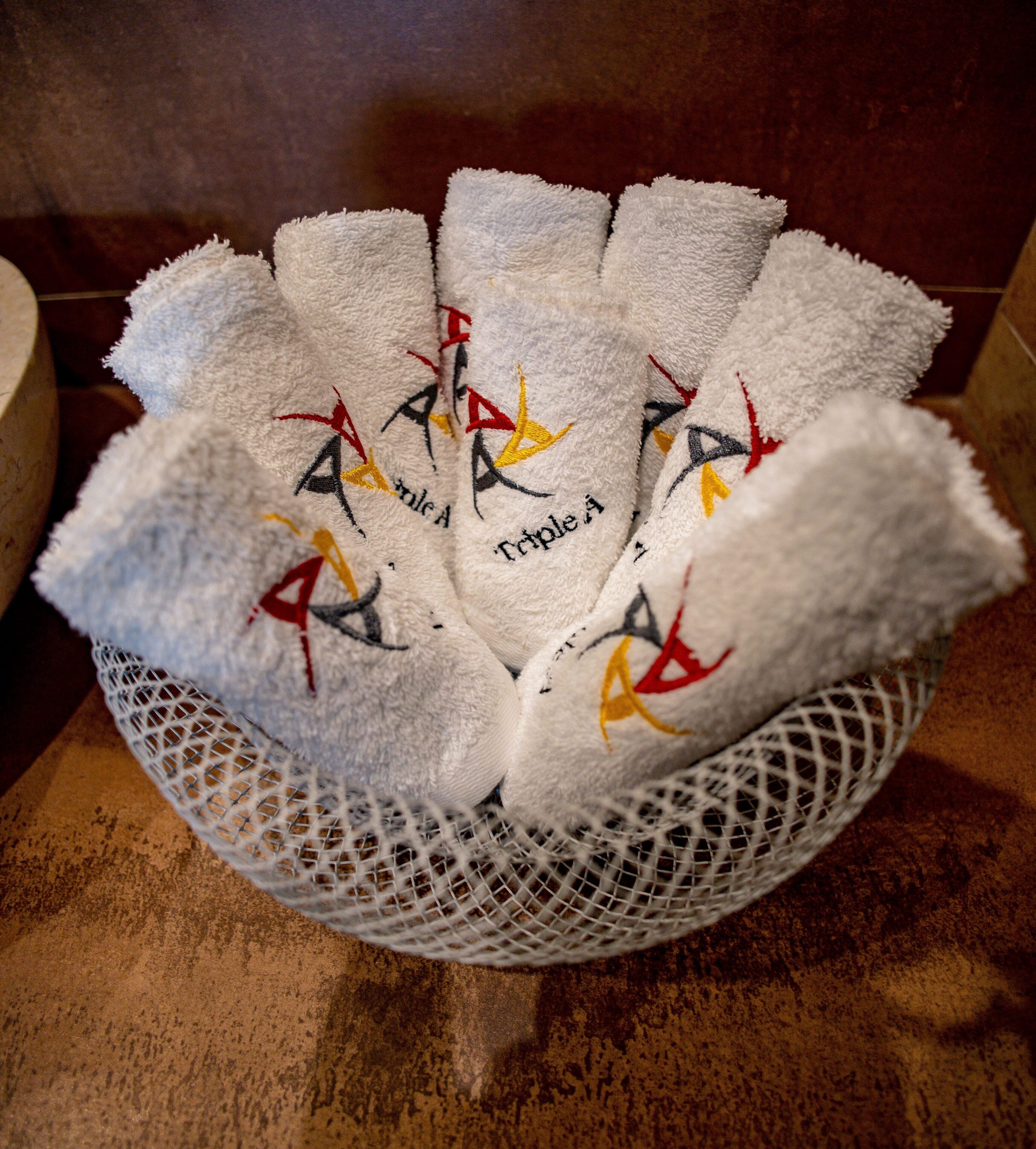 Un panier rempli de serviettes blanches ornées de logos brodés.