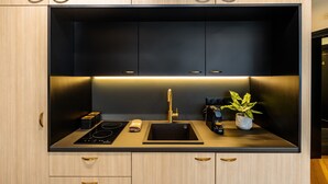 A modern kitchen with a black countertop, stainless steel appliances, and wooden cabinetry. - Triple A - Kolokotroni 62 (Athens)
