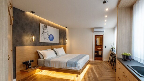 A modern bedroom with a wooden bed, bedside tables, and a wall-mounted artwork. - Triple A - Kolokotroni 62 (Athens)