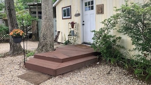 Een klein, gelijkvloers houten vakantiehuisje met een voordeur, een klein terras en een brievenbus.