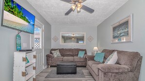A living room with two brown sofas, a black ottoman, a ceiling fan, a TV, and a framed picture on the wall. - Cute Cozy Beach Bungalow
golf cart available Commercial Ice maker for the cooler (Myrtle Beach)