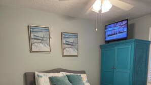 A bedroom with a bed, a nightstand, a teal wardrobe, and two framed pictures on the wall. - Cute Cozy Beach Bungalow
golf cart available Commercial Ice maker for the cooler (Myrtle Beach)