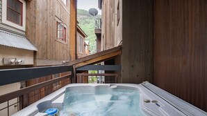 Un jacuzzi en un espacio exterior estrecho, flanqueado por edificios de madera.