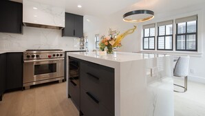 Una cocina moderna con una isla central, horno integrado y muebles oscuros.