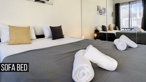 Une chambre d’hôtel moderne dotée d’un canapé-lit, d’un grand miroir et offrant une vue sur l’extérieur.