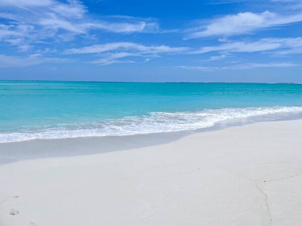 Una spiaggia con acque cristalline turchesi e una vasta distesa di sabbia.