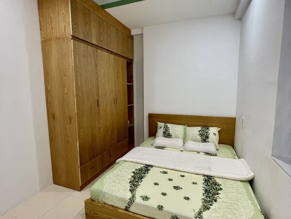 Un dormitorio con un armario de madera, una cama con ropa de cama floral y una mesita de noche pequeña.