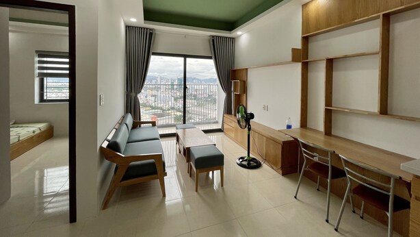 Ein modernes Wohnzimmer mit einer Couch, Sesseln, einem Esstisch und Blick auf die Stadt durch große Fenster.